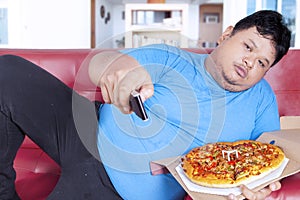 Obese man holds pizza and remote 1