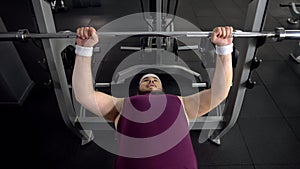 Obese man lifting up barbell, personal gym workout plan, desire to be strong