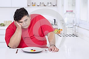 Obese man looks bored to eat healthy salad