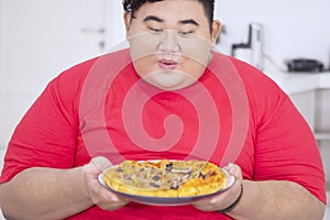 Obese man looks happy while holding a tasty pizza