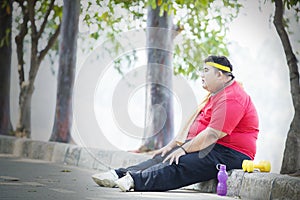 Obese man looks pensive after exercise in the park