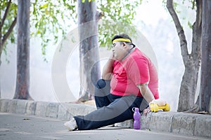 Obese man looks pensive after exercise in the park