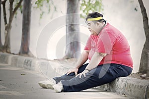 Obese man looks tired after exercising in park