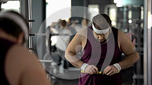 Obese man measuring fat waist, checking result after dieting and training health