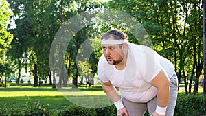 Obese man running outdoors, out of breath, overcoming laziness and insecurity