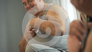 Obese man sitting on front of mirror and looking at family photo with love