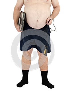 Obese man stands with scales and skipping rope