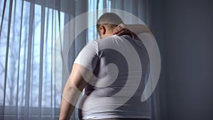 Obese man stretching neck muscles, back pain problems caused by overweight