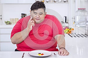 Obese man thinking something while eating salad