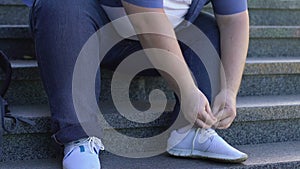Obese man tying shoelaces with difficulty, problems with extra weight, health