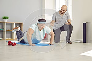 Obese, overweight woman working out with personal trainer in gym