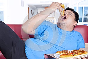 Obese person bite a slice of pizza