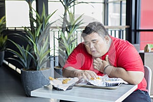 Obese person looks getting heart attack in cafe