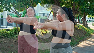Obese two young asian woman doing stretching arm muscle in the park.