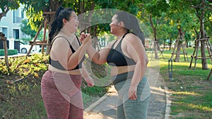 Obese two young asian woman doing stretching arm muscle in the park.