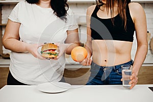 Obese woman with burger and dietitian with fruits