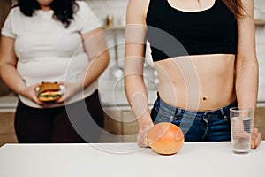 Obese woman with burger and dietitian with fruits