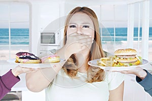 Obese woman closed mouth for unhealthy food