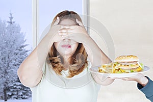 Obese woman closing eyes for junk food