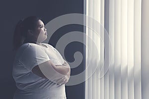 Obese woman daydreaming by the window