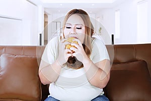 Obese woman with delicious cheeseburger at home