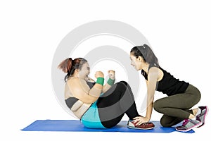 Obese woman doing sit up with instructor