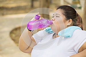 Obese woman drinking water after doing a workout