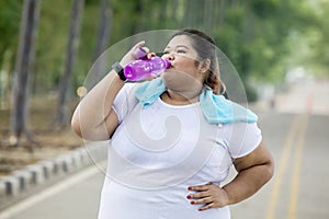 Obese woman drinking water on the road