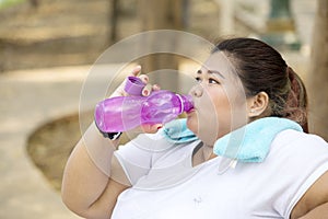 Obese woman drinks water after doing a workout