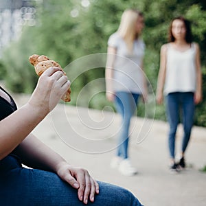 Obese woman eat junk food at fit people background