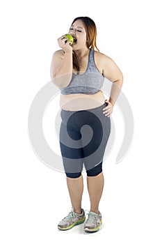 Obese woman eating an apple on studio