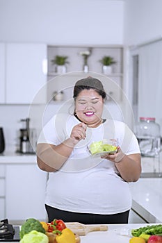 Obese woman eating a bowl of healthy salad