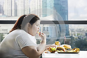 Obese woman eating french fries in the restaurant