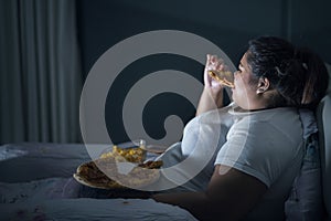 Obese woman eating pizza before sleep