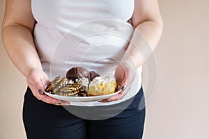 Obese woman eating sweets holding plate of cookies