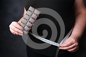 Obese woman with fattening food and measure tape