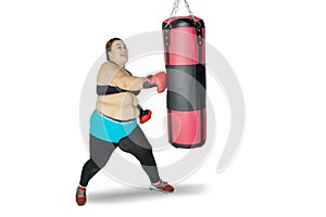 Obese woman hitting a boxing bag on studio