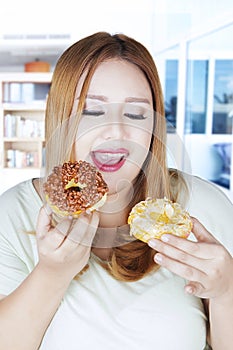 Obese woman holding two donuts