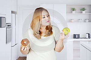 Obese woman holds apple fruit and donuts