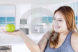 Obese woman holds fresh apple