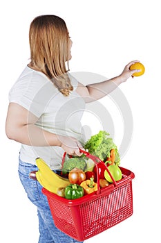 Obese woman holds fresh orange