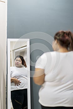 Obese woman looking at her fat belly in the mirror