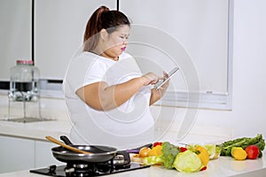 Obese woman looking at recipes on a tablet
