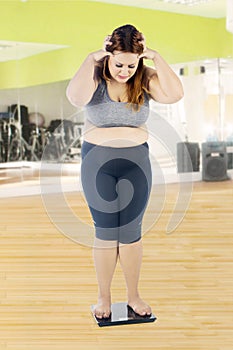 Obese woman looking weight scale