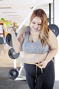 Obese woman with measure tape and apple