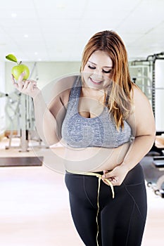 Obese woman measuring her belly at gym