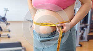 Obese woman measuring her waist at gym