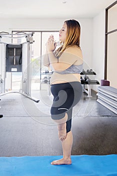 Obese woman practicing yoga in fitness center