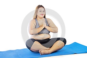 Obese woman practicing yoga while sitting on mat