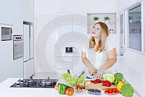 Obese woman preparing vegetable to make salad